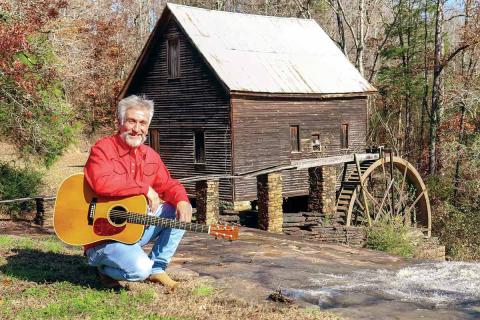 Musician Danny Thomas poses with his guitar in front of Ragsdale Grist Mill in Homer (Banks County).