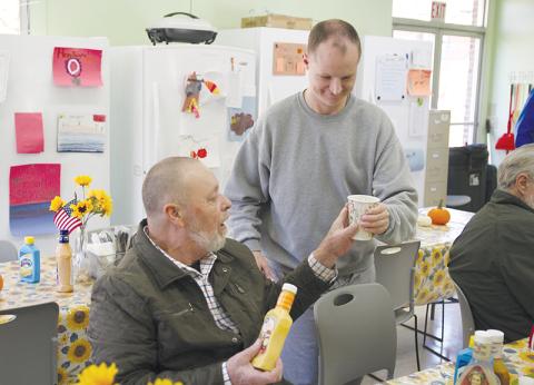 Michael Parks, right, brings a beverage to Bruce Fry of Clarkesville at the Clarkesville Soup Kitchen on Monday afternoon.