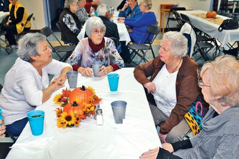 Karen Katz, Patsy Edwards, Barbara Land and JoAnn Cross (clockwise from left) converse just before the Thanksgiving meal at the Habersham County Senior Center on Friday. The friends were part of a record crowd at the meal with more than 140 guests.