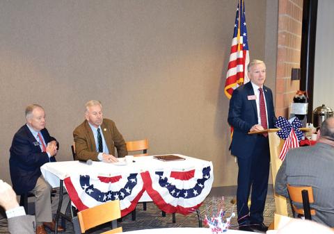 Georgia Rep. Chris Erwin speaks at the dais while fellow legislators Sen. John Wilkinson (left) and Rep. Terry Rogers wait their turns to speak at Tuesday’s legislative breakfast at North Georgia Technical College.