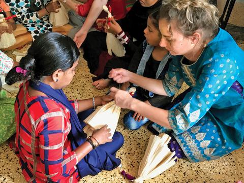 Sarah Samsel (right) teaches children in India how to make corn husk dolls during her mission trip in January.