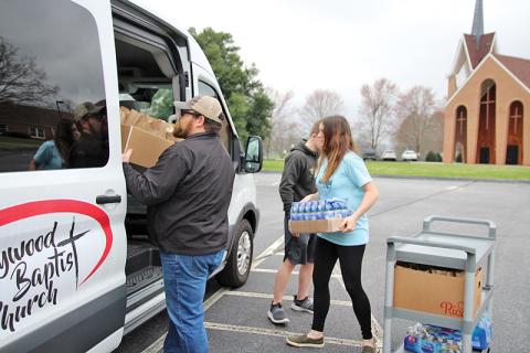 Chuck Johnson with Hollywood Baptist Church, Nathan Rhoads and Jessie Smith with Bethlehem Baptist load up a van with sack lunches that were distributed to families Monday.