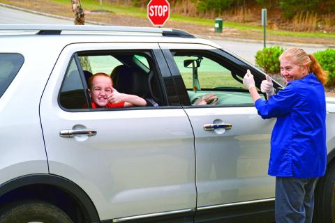 Fairview Elementary student Dennis Harkins gives Malinda Lathan and other school nutrition associates a thumbs up during the meal pickup at Fairview Elementary on Thursday. Free meals for students 18 and under are available at all elementary schools in Habersham County Monday through Friday from 11:30 a.m. to 12:30 p.m. Photo by ALAN NESMITH