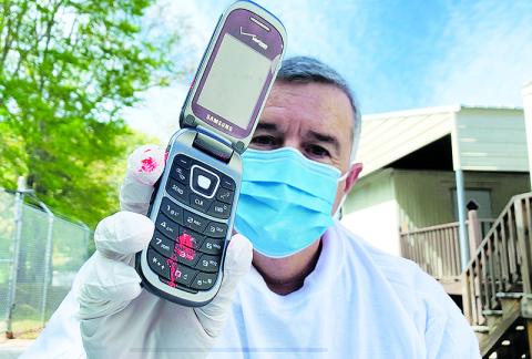 Habersham County Emergency Services Director Chad Black demonstrates in a public service video Wednesday how wearing gloves can cross contaminate personal items, such as a cell phone, using fingerprint powder.