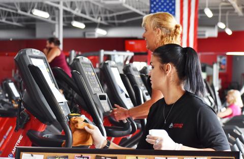 Ariel Coones, a trainer at Workout Anytime in Cornelia, sanitizes one of the many ellipticals. The staff plans to regularly clean the gym equipment now that members have returned.