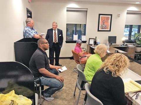 Trent Davis (seated left) listens to the Board of Elections’ announcement of the recount results Monday night.