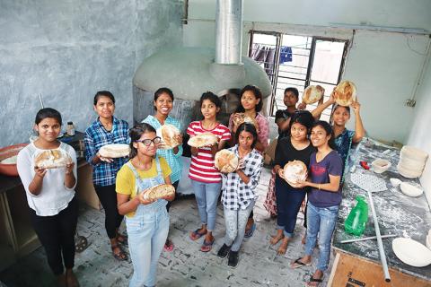 Neha, Pooja, Rajni, Jyoti, Mamta, Gayatri, Kajal, Kanchan, Tulsi, Angel and Taniya show off their freshly-baked bread after a class with Clarkesville bakery owner AJ White in India.