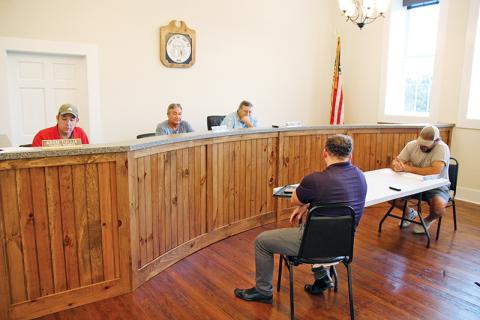 Mt. Airy Council members Adam Tullis, Ray McAllister and Mayor Pro-Tem Mike McCoy discuss the town millage rate Wednesday night. Seated below are councilmen Patrick Leford and Chris Green.