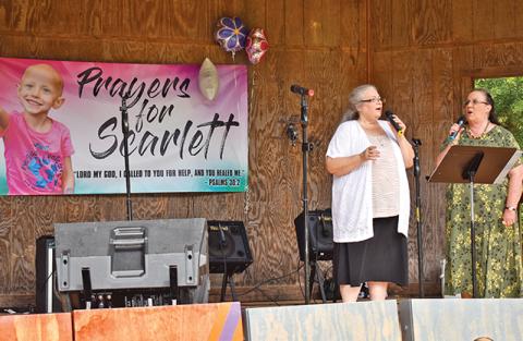Renee Johnson and Connie Perry sing during the benefit for Scarlett LaCount at Pitts Park on Saturday.