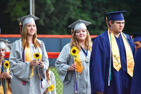 Habersham Central graduates (from left) Rachel Jenkins, Ellawyn Ketch and Nathan Luders prepare to walk onto John Larry Black Field on Friday night for the graduation ceremony. Below, many graduates decorated their caps with messages. 