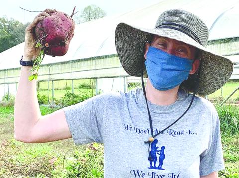 Melon Head Farm Manager Emma Courson shows off a giant sweet potato. Photo courtesy of Joni Kennedy