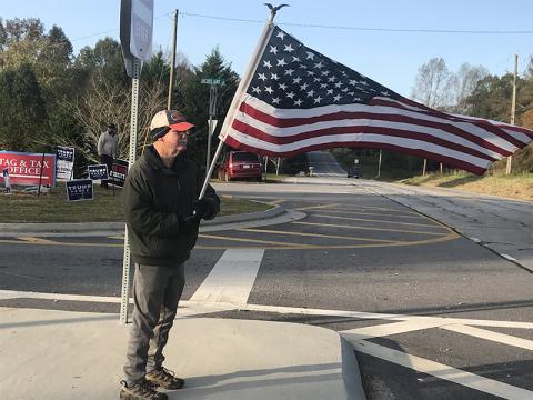 A man who described himself only as a "proud American" waves Old Glory in front of the Ruby Fulbright Aquatic Center on Tuesday morning as folks came to vote.