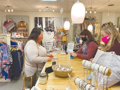 Sarah Mobley purchases a pair of earrings from Erin London Store in Clarkesville on Small Business Saturday as Meg Luke (left behind counter) and Jeanie Huddleston help out.
