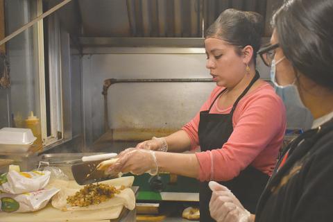 El Carreton Co-Owner Marisela Gonzalez and Jennifer Martinez prepare a shrimp burrito for a takeout order Tuesday evening in Cornelia.