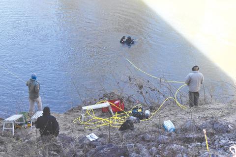 Officers from Georgia State Patrol monitor divers in the Chattahoochee River on Thursday afternoon as they search for the missing gun in a Jan. 18 shooting.