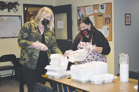 Lindsey Sloan, one of the lead volunteer coordinators at the Lord’s Help Soup Kitchen, and Marina Long package to-go plates in a bag.