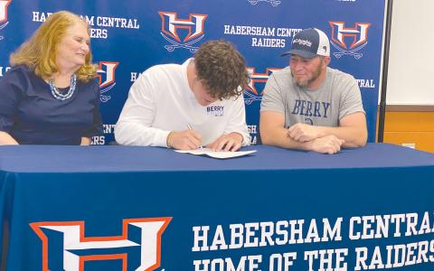 Parker Behrends (center) signs his national letter of intent April 29 to become the latest Raider to continue his track and field career at Berry College. With Behrends are his grandmother Mary Behrends and father Ray Behrends. ISAIAH SMITH/Staff 