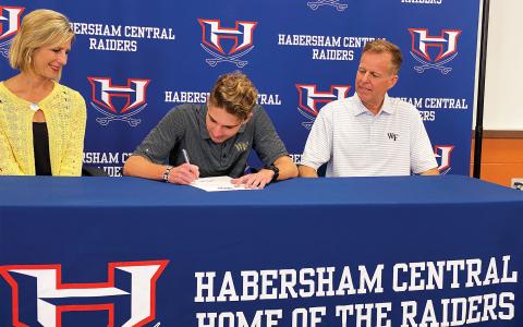 Andrew Kivett (center) signed his national letter of intent last Thursday to run track and cross country at Wake Forest. Pictured with him are his parents Luci (left) and Ed (right) Kivett. ISAIAH SMITH/Staff 