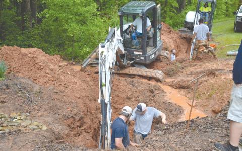 Workers from Demorest’s water department look to repair the pipe damaged Tuesday morning by a freak lightning strike that melted at least one section of a water pipe (inset) and left a trench through the woods. MATTHEW OSBORNE/Staff