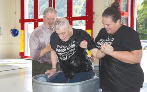 Chaplain Tom Wagner (left) and caretaker Erin Murray (right) help Wayne Ivester out of the portable baptismal pool at the new  Cornelia Fire Department South Station. CHAMIAN CRUZ/Staff