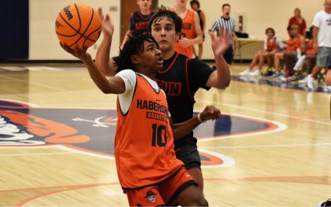 Enzo Combs extends the ball to avoid the defense before finishing a layup in the Raiders summer game against Rabun County last Friday. ISAIAH SMITH/Staff 