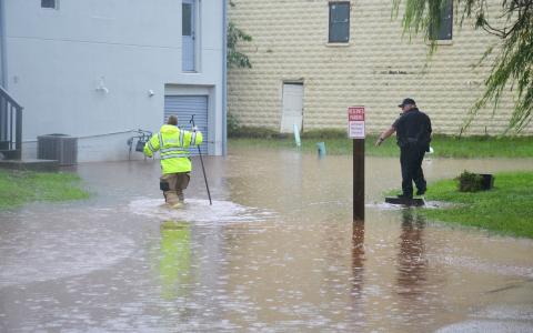 Cornelia first responders wade through a flooded parking lot outside of  Structure Hair Studio in Cornelia on Tuesday afternoon. BRIAN WELLMEIER/Staff