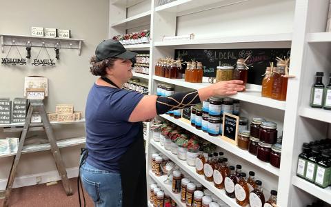Mandy Hicks organizes her wall of Amish-made jellies and other delights at Mountainside Exchange in Clarkesville. MATTHEW OSBORNE/Staff