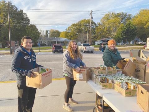 From left, Herber Morales, Kimberly Allen, Andrea Armour handle boxes of food for those in need. 