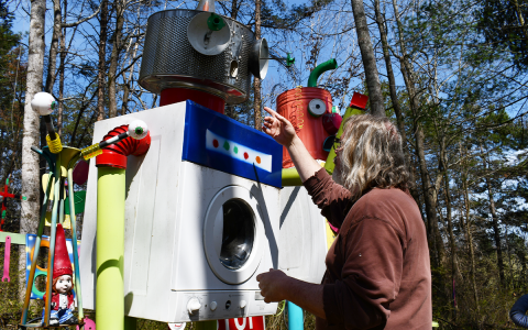 Artist Sam Granger gestures at one of his art creations on his Habersham County property. BRIAN WELLMEIER/Staff 