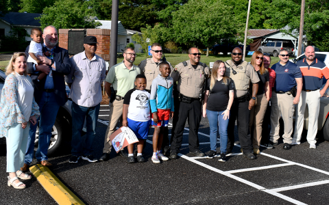 The group of officials honoring Canada (middle, red shorts) included Principal Fran Blackburn, Assistant Principal Kevin Weems with Kingston Winters, Victor Scott, Investigator Cale Garrison, Logan’s brother Elijah Shields, Deputy Travis Cross, Deputy Daniel Seeley, Deputy Kayla Neal, Deputy Chase Trammel, Deputy Heidi Lass, Director of Elementary Schools Patrick Franklin, Col. Murray Kogod and Superintendent Matthew Cooper. MATTHEW OSBORNE/Staff