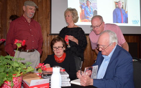 Loran Smith signs copies of his new book while his wife Myrna greets and mingles with fans at the Community House in Cornelia. BRIAN WELLMEIER/Staff