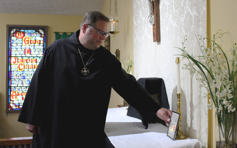 Father Damien Trudeau prepares the altar to host a funeral mass at St. Thomas Anglican Church in Alto. AMARIS E. RODRIGUEZ/Staff