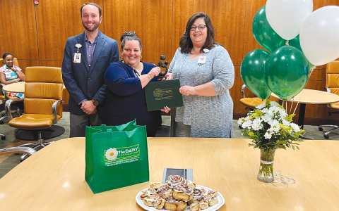 Marlana Kennedy (middle) smiles as she receives her DAISY Award from nursing Director Valerie Lewis and CEO Tyler WIlliams. Cinnamon buns are the signature food of the award, based on its foundation’s namesake. MATTHEW OSBORNE/Staff