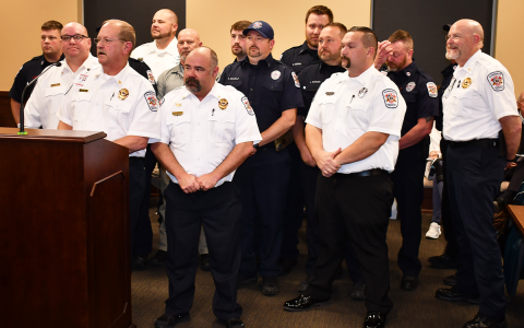 Habersham County Emergency Service employees (from left) Jeff Brown, Jason Davey, Chief Jeff Adams, Jason Garrett, Brad Davidson, Ronnie Davis, Bryan Nix, Randi Seabolt, Mark Gerrin, Jeff Parker, Mack Palmer, Jamie Tyler, Royce Eller and Bill Ramsey stand up in solidarity at Thursday’s special called meeting of the Habersham County Board of Commissioners. MATTHEW OSBORNE/Staff
