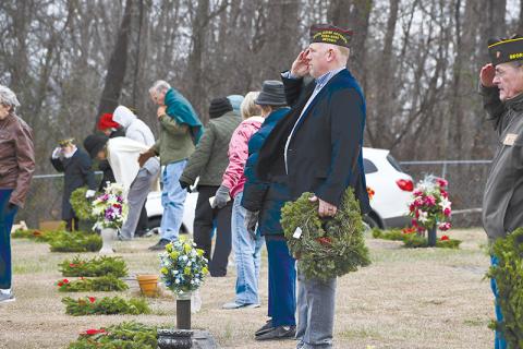 rant-Reeves VFW Post 7720 Commander Bill Miles salutes after placing a wreath on the grave of a veteran at the VFW Memorial Park on Saturday as part of the Wreaths Across America program. Volunteers helped place all the wreaths throughout the cemetery.