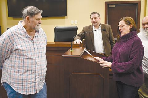 David Barrs (left) listens to a heartfelt speech by colleague Laurie Church at Monday’s county commission meeting as Commissioner Ty Akins looks on.