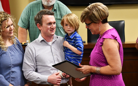 Chandler Franklin, 4, is honored by County Manager Alicia Vaughn along with his parents Clayton and Allyson, at Monday’s Board of Commissioners meeting. Commissioner Bruce Palmer and the rest of the board thanked the young man for his alertness to a county utility malfunction. MATTHEW OSBORNE/Staff