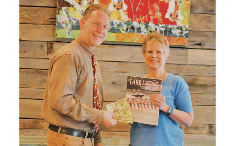 Melissa Elzey won the Spring 2023 Lake Living cover contest with her capture of the Lake Burton Ski Patriots’ performance on July 4, 2021. She is shown getting her prize from Clayton Tribune publisher Enoch Autry. CLAYTON TRIBUNE/Special
