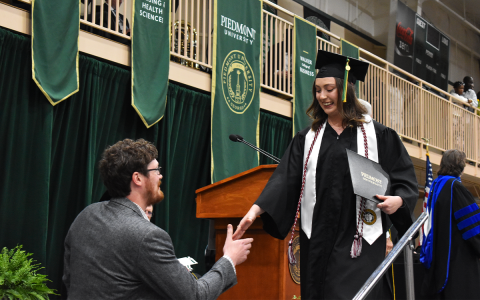 Samantha Carvallo takes a helping hand from digital marketing manager Zack Hoopaugh after receiving her degree Friday at Piedmont University’s graduation ceremony. Carvallo graduated with a Bachelor of Arts degree and majored in art during her time at Piedmont. EMMA MARTI/Staff