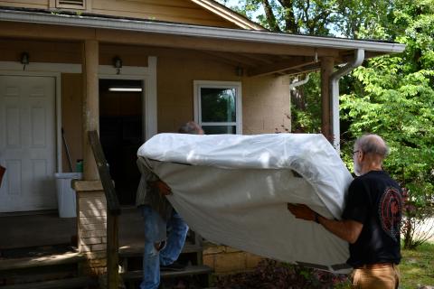Brad White and Mike Miller bring a mattress inside the home beside Victory Baptist Church. Originally a larger house, the unit was split to accommodate two small families or two individuals. JOHN DILLS/Staff