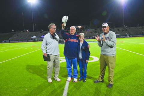 Glenn Jones and his wife Susan acknowledge the Raider crowd Friday night at halftime after being honored for his 46 years of public address announcing at the school. They are joined by athletic director Geep Cunningham (left) and Principal Dr. Jonathan Stribling. TOM ASKEW/Special