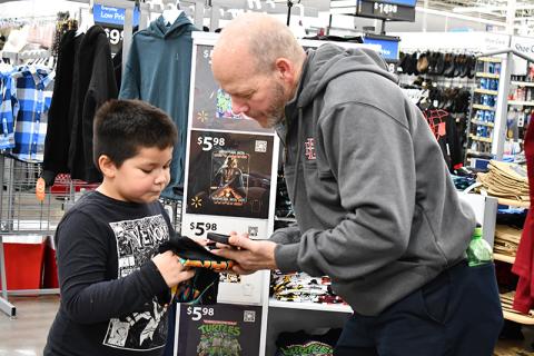 First grader Zayden Tomas Wade picks out a Star Wars T-shirt with Baldwin Fire Chief Joe Roy, organizer of Shop with a Hero. JULIANNE AKERS/Staff