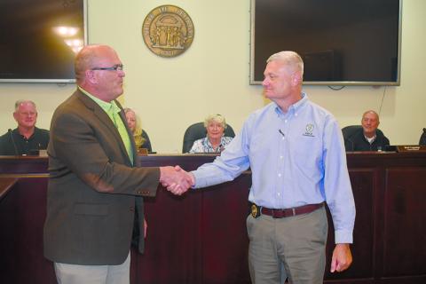 Clarkesville’s new police chief Danny Clouatre (right) shakes hands with City Manager Keith Dickerson at Monday’s meeting. MATTHEW OSBORNE/Staff