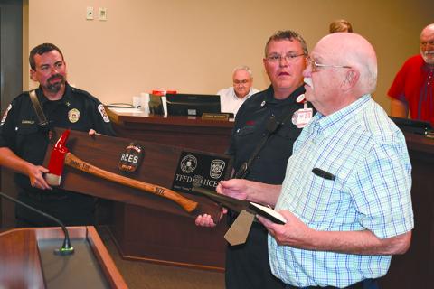 Habersham County Emergency Services Battalion Chief Dwight McNally (left) and firefighter Kyle Cash help present Jimmy Yon with a commemorative fireman’s axe at the April meeting of the Habersham County Board of Commissioners. MATTHEW OSBORNE/Staff