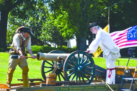David Louden (left) and Ed Hendricks, dressed in Revolutionary War regalia, service a Revolutionary artillery cannon after it was set off at a Flag Day ceremony to honor Old Glory. JULIANNE AKERS/Staff
