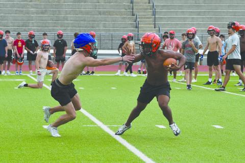Teammates look on at Monday’s practice as ballcarrier Donnie Warren looks to shake off Landyn Savage. LANG STOREY/Staff