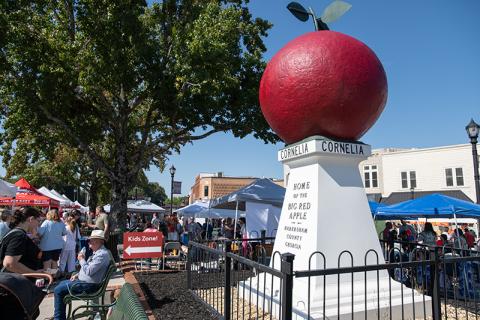 The Big Red Apple sits in the sun in downtown Cornelia on Saturday, surrounded by people. ZACH TAYLOR/Staff