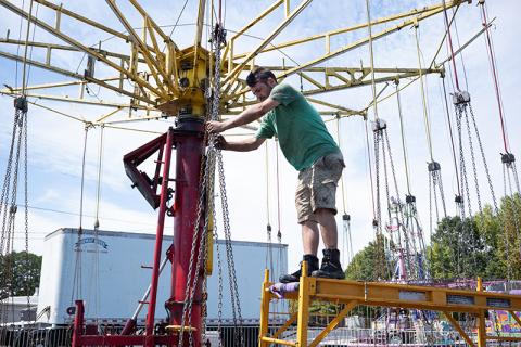 Tim McCoy adjusts the chains on the swing ride before testing its functionality. ZACH TAYLOR/Staff