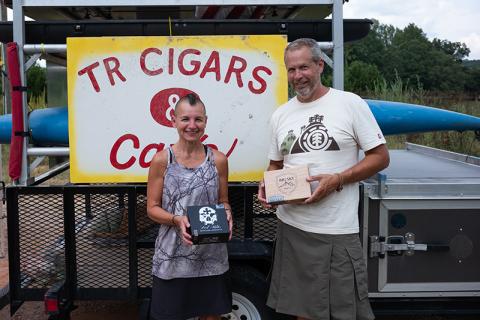 Tim Ganley and Vie Binga pose in front of the TR Cigars sign at Amy’s Creek Farmer’s Market. The pair sells handmade cigars from the market on the weekends and most weekdays, weather permitting. ZACH TAYLOR/Staff