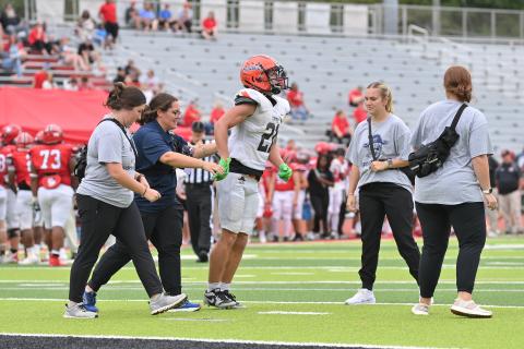 Head Athletic Trainer London Addison (navy shirt) and AT students from UNG and Piedmont help Raider football player Landyn Savage off the field during a game this season. TOM ASKEW/Special